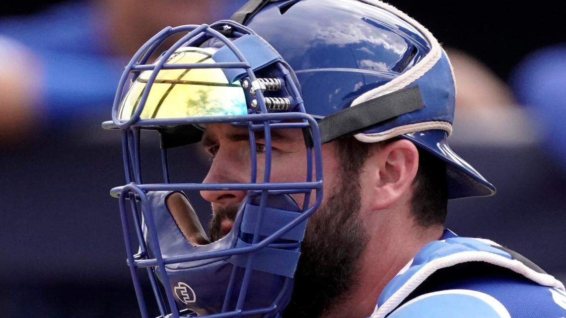 Kansas City Royals catcher Cam Gallagher uses a wrist-worn device used to call pitches during the sixth inning of a spring training baseball game against the Seattle Mariners, Tuesday, March 29, 2022, in Peoria, Ariz. The MLB is experimenting with the PitchCom system where the catcher enters information on a wrist band with nine buttons which is transmitted to the pitcher to call a pitch. (AP Photo/Charlie Riedel)