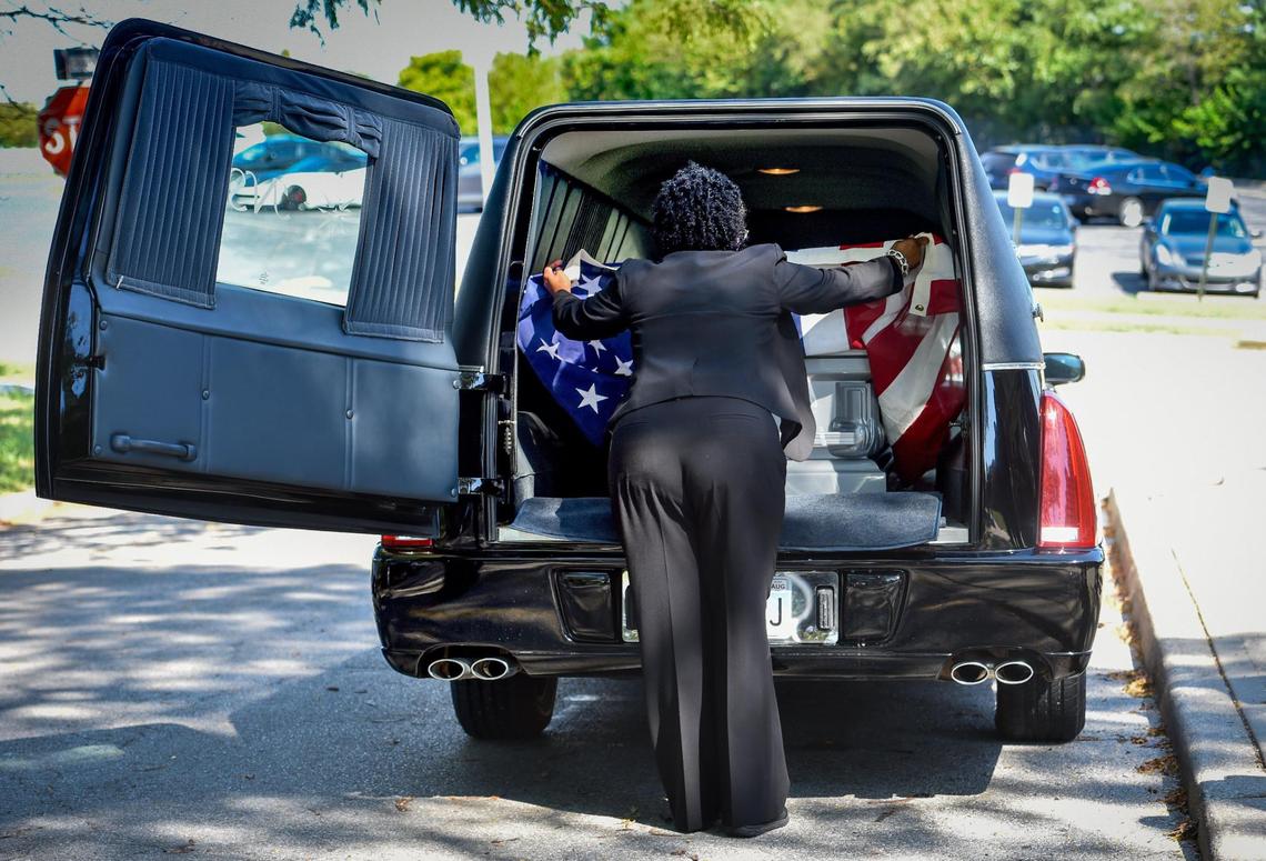 Mortician Gwendelrae Hicks of Northern Star Mortuary gently folds a corner of an American flag covering a casket after a Sept. 15 funeral in Kansas City.