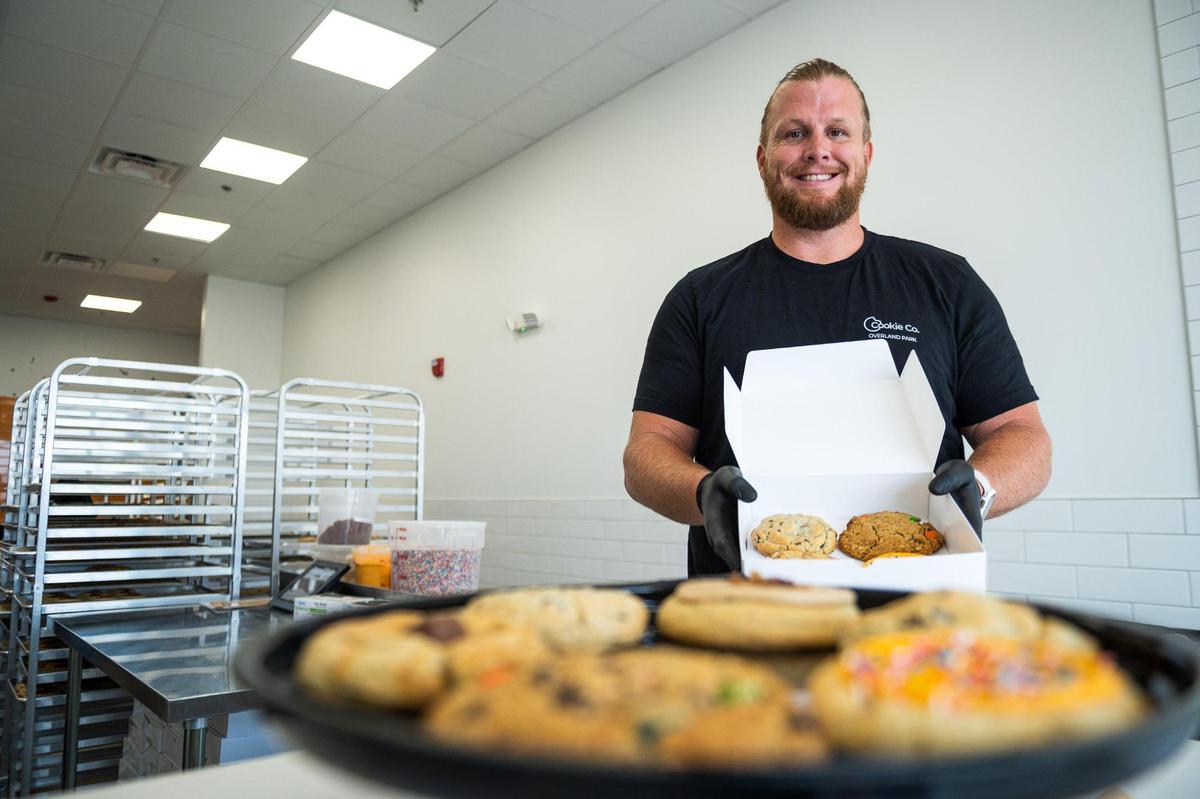 Former Kansas City Chiefs offensive lineman Jordan Devey holds up a box of cookies at his gourmet cookie shop in Overland Park.