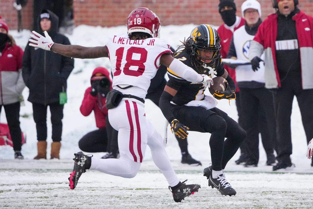 Missouri Tigers wide receiver Marquis Johnson runs the ball against the defense of Arkansas Razorbacks safety TJ Metcalf during the regular-season college football finale for both teams at Faurot Field at Memorial Stadium in Columbia on Saturday, Nov 30, 2024.