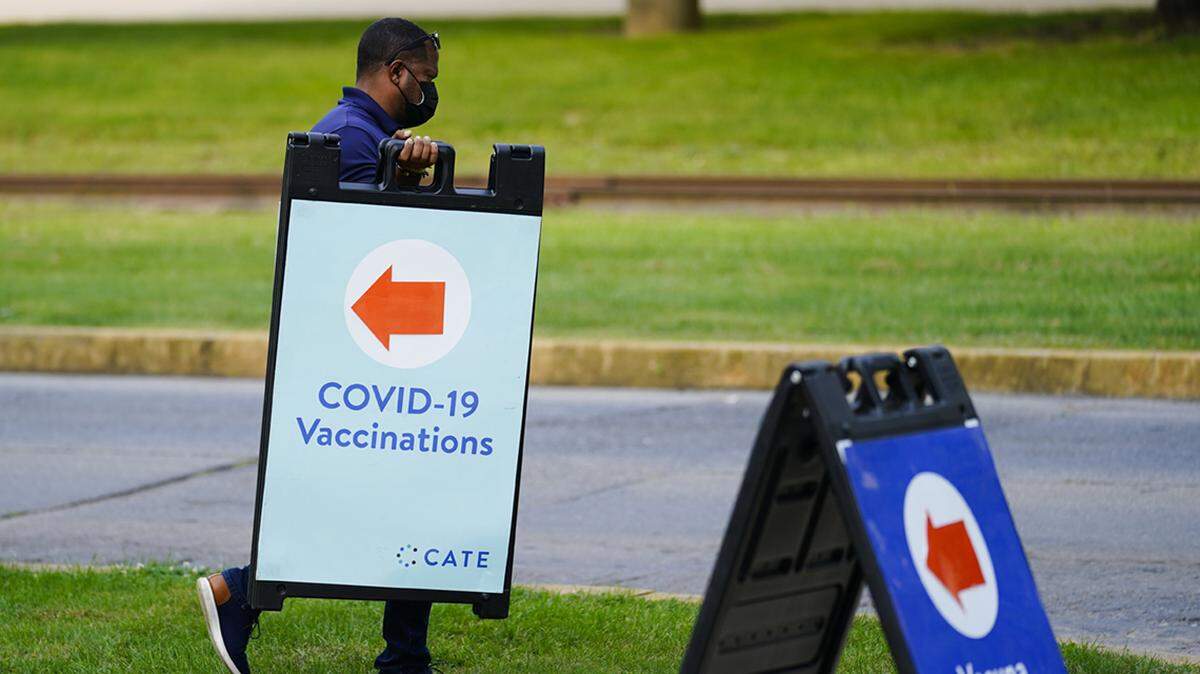 FILE - In this Sept. 14, 2021, file photo, a worker posts placard for a COVID-19 vaccination clinic at the Reading Area Community College in Reading, Pa. With more than 40 million doses of coronavirus vaccines available, U.S. health authorities said they’re confident both seniors and other vulnerable Americans seeking booster shots and parents anticipating approval of initial shots for young children will have easy access. (AP Photo/Matt Rourke, File)