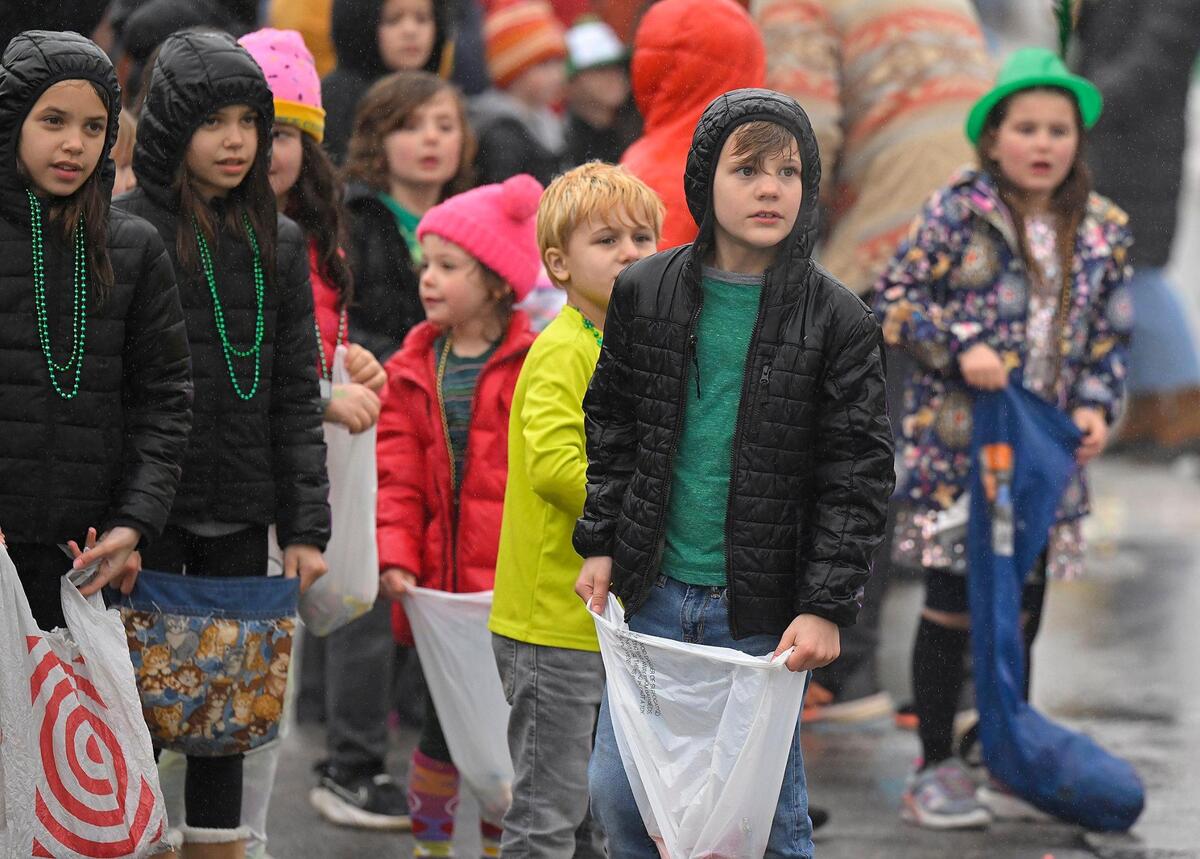 Kids, wet from the rain, waited for candy to be tossed from the floats during the 2023 Brookside St. Patrick’s Day Warm-Up Parade on Saturday March 11, 2023 in Kansas City.