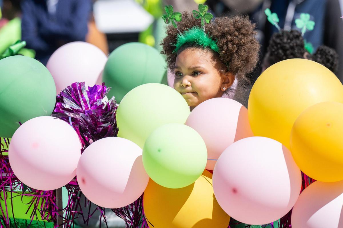 A little girl pokes her head out from balloons on a float during the Kansas City St. Patrick’s Day Parade on Monday, March 17, 2025.