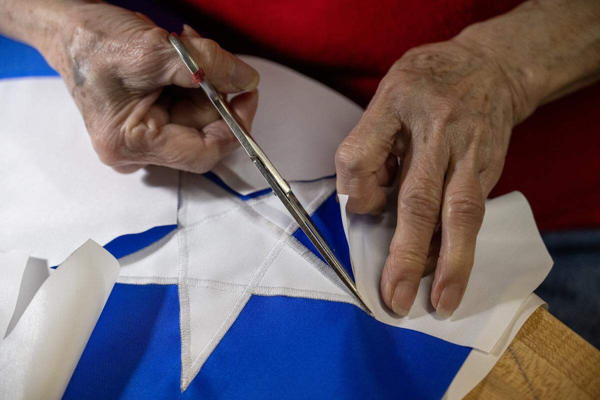 Seamstress Phuong-Thu Nguyen, 78, a native of Vietnam who has been sewing flags at All Nations Flag Co., for over 40 years, uses scissors to trim excess fabric from around a star on a flag of the nation of Curaçao. Nguyen was making the flag aton Thursday, Jan. 8, 2026, in Kansas City.