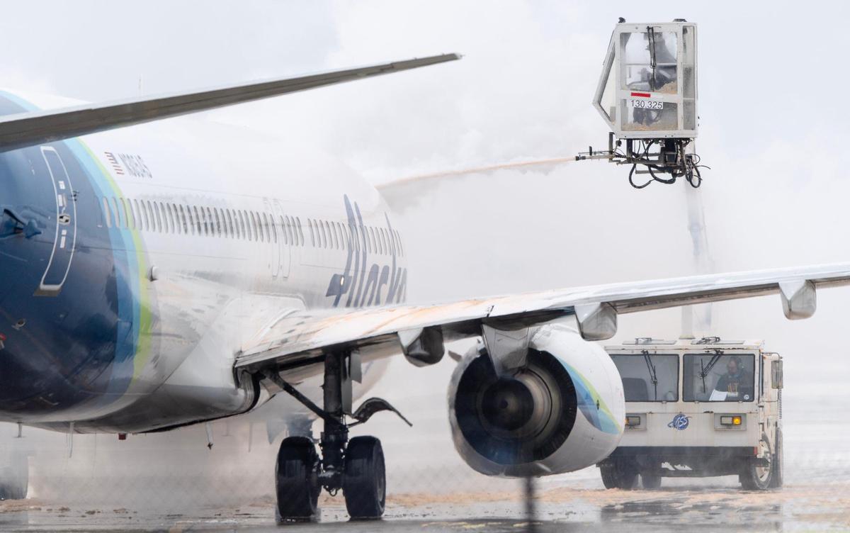 A ground crew member deices an Alaska Airlines Boeing 737 passenger jet at Kansas City International Airport on Thursday, Dec. 22, 2022, in Kansas City.