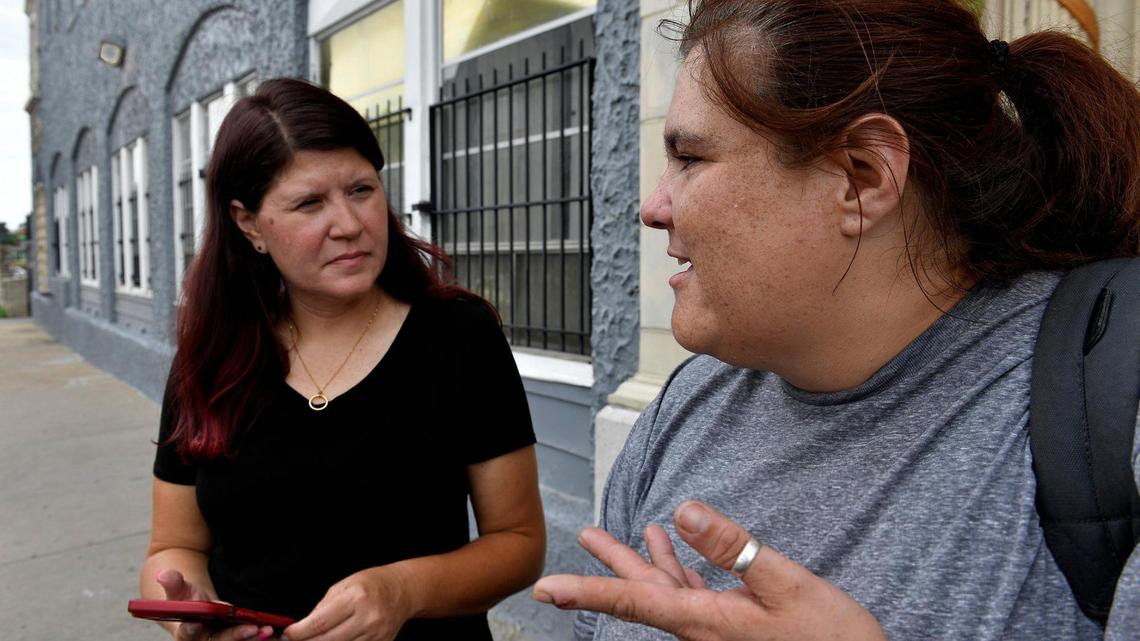 Outside a midtown apartment building, Jennifer Hull, left, a street outreach worker, talks with Christina Smith, right, about finding permanent housing. Smith is currently staying at a motel, but her time there expires on Monday.