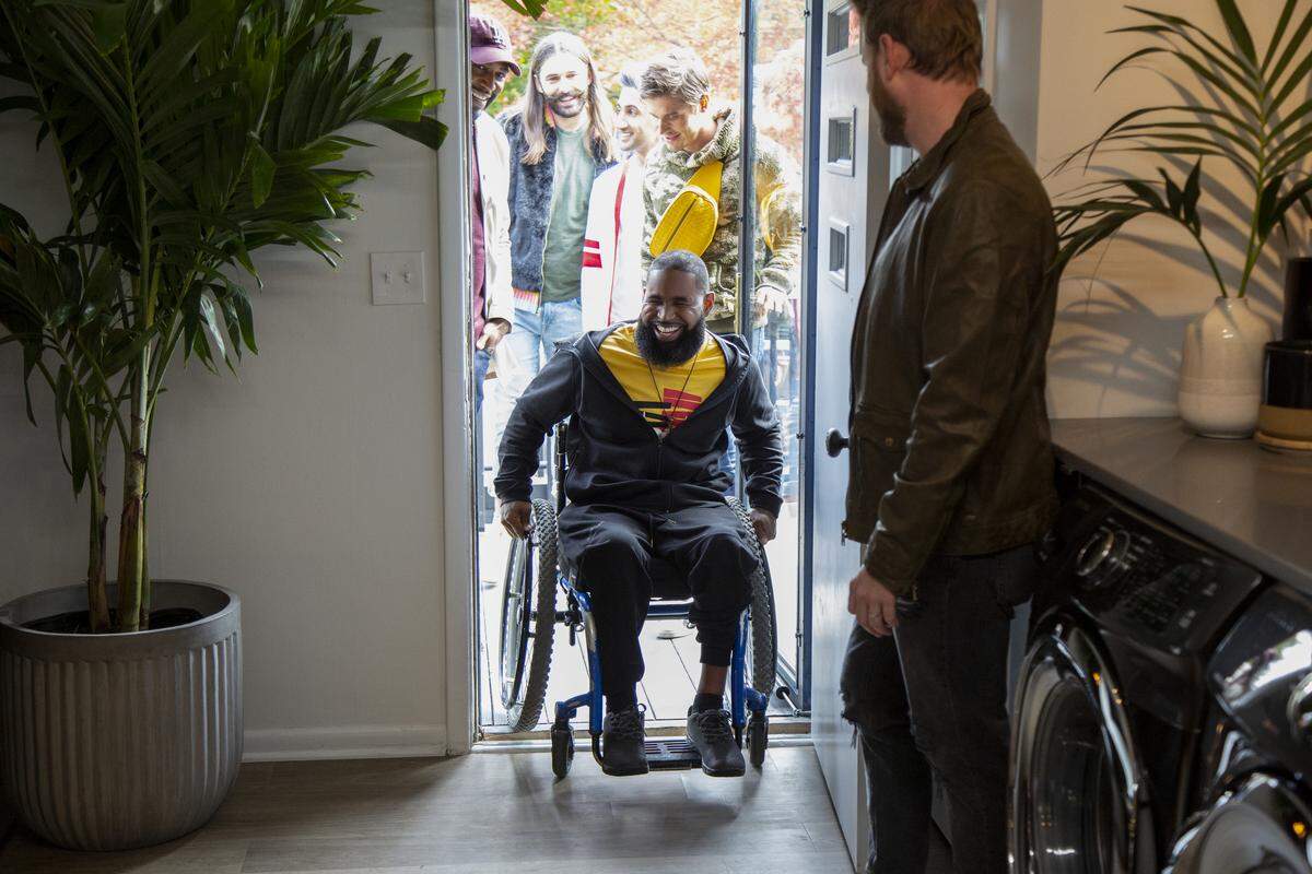 Wesley Hamilton rolls his wheelchair into his remade home, accompanied by “Queer Eye” guys, from left, Karamo Brown, Jonathan Van Ness, Tan France, Antoni Porowski and Bobby Berk.