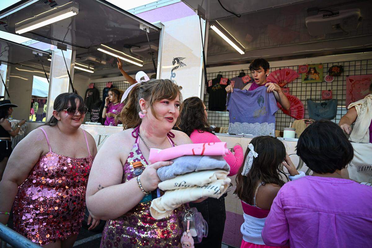 Shelby Hollman, Kansas City, walks away from a merch stand with stack of clothing before the Chappell Roan concert on Saturday, Oct. 4, 2025, at the National WWI Museum and Memorial in Kansas City.