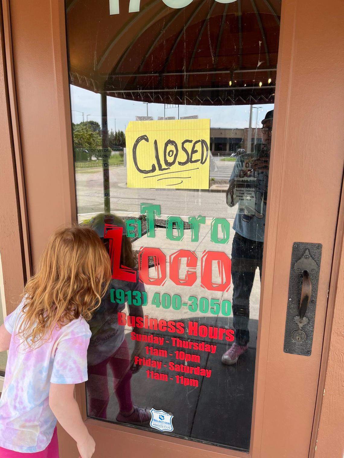 In July, a child peers through the door of the closed El Toro Loco after immigration law enforcement officers arrested at least seven staff members at their restaurant location in Kansas City, Kansas.
