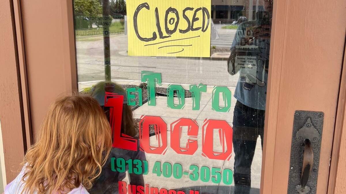 A child peers through the door of the closed El Toro Loco after immigration law enforcement officers arrested at least seven staff members at their restaurant location in Kansas City, Kansas.