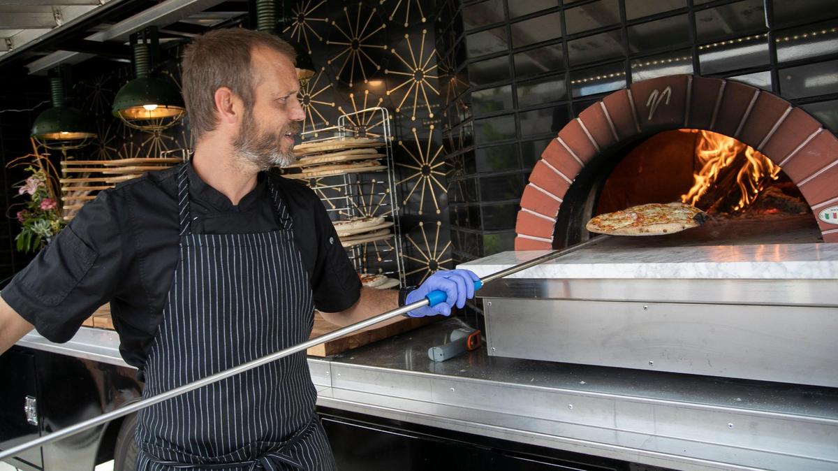 Dispatch Pizza owner Jeremy Long takes a pizza out of the wood-burning stove on the 1949 International Harvester KB7 he converted to a food truck.