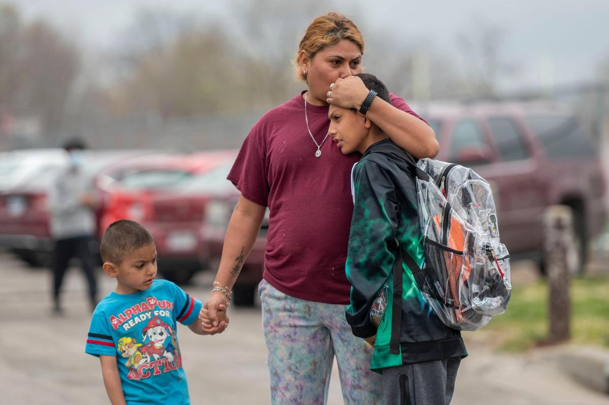 Parents wait outside Northeast Middle School to pickup their children after one person was injured in a stabbing on Tuesday April 12, 2022, at the school in Kansas City. The victim was taken to the hospital with life-threatening injuries, said Officer Donna Drake, a spokesperson for the Kansas City Police Department. One person has been detained.