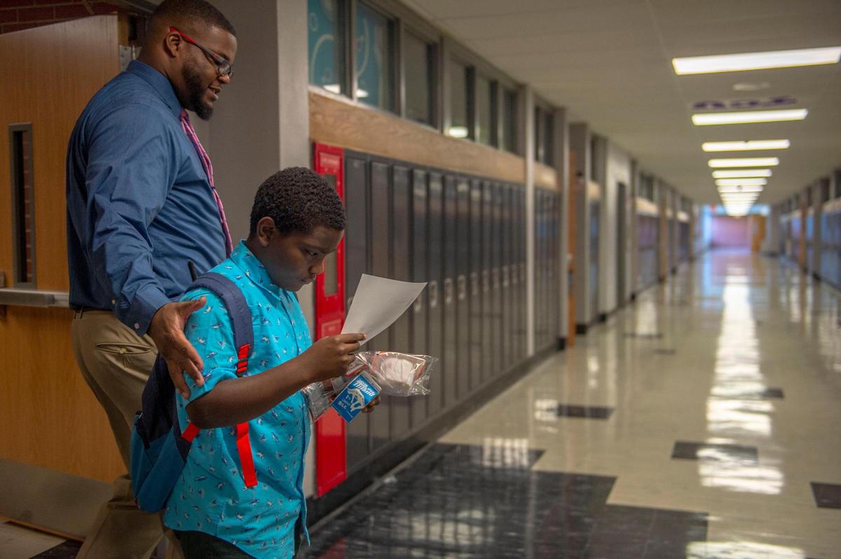 Nowlin Middle School Assistant Principal Roy King helps 11-year-old Cordei Mclaughlin find his classroom on his first day as a sixth grader in Independence.