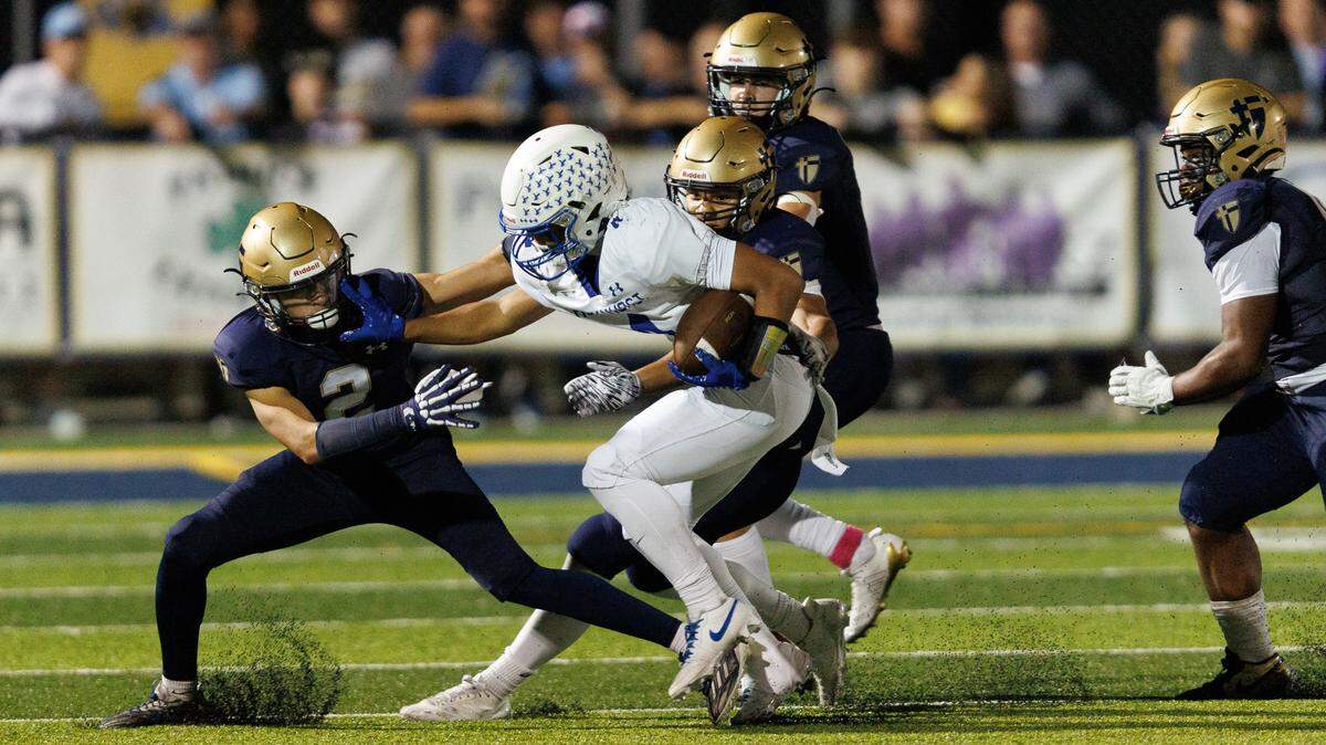 Rockhurst’s Blake Thomas tries to hold off Saint Thomas Aquinas defenders during the Hawklets’ 36-35 overtime victory in a high school football showdown on Friday, Oct. 10, 2025.