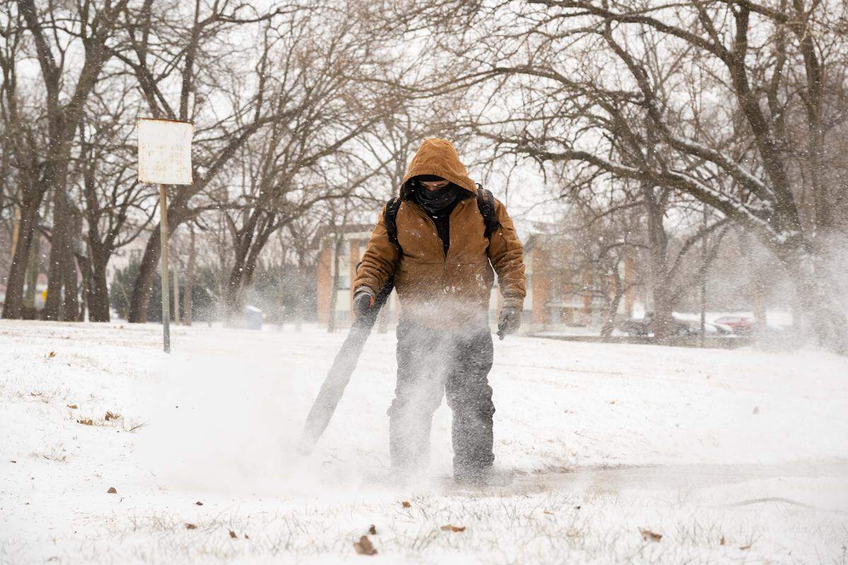 Snow removal crews blew snow off sidewalks near Midtown on Saturday, January 24, 2026, in Kansas City. Subzero temps and light snow moved into the area overnight.