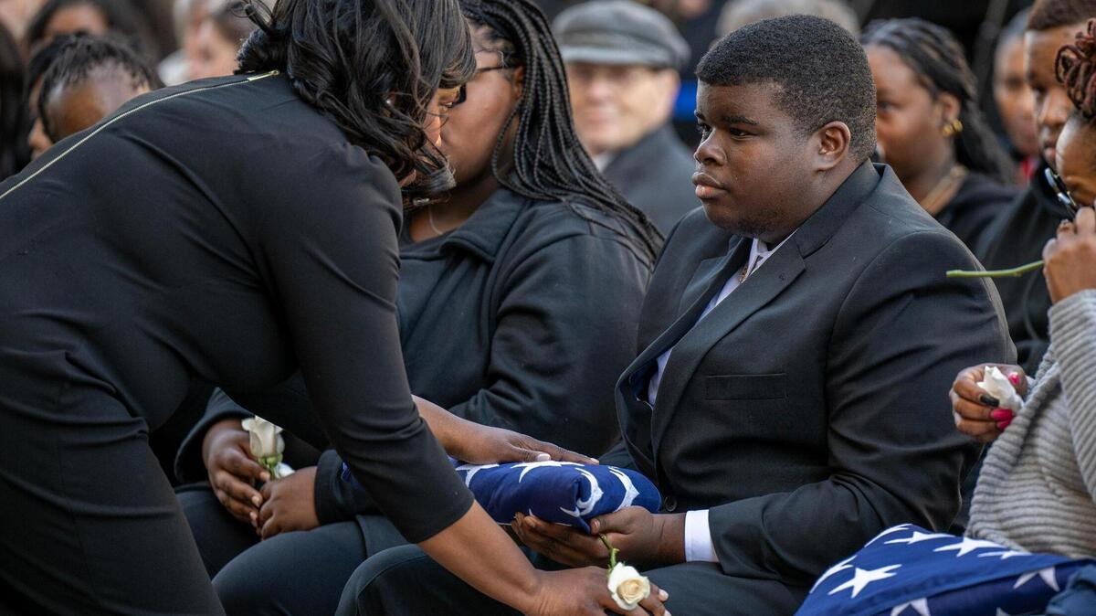 Drexel Mack Jr., son of Drexel Mack, a civil process officer with Jackson County courts who was shot and killed during an eviction, is given a U.S. flag from Jalilah Otto, Judge of Jackson County 16th Circuit Court, Monday during a memorial service for his father at the Jackson County Courthouse.