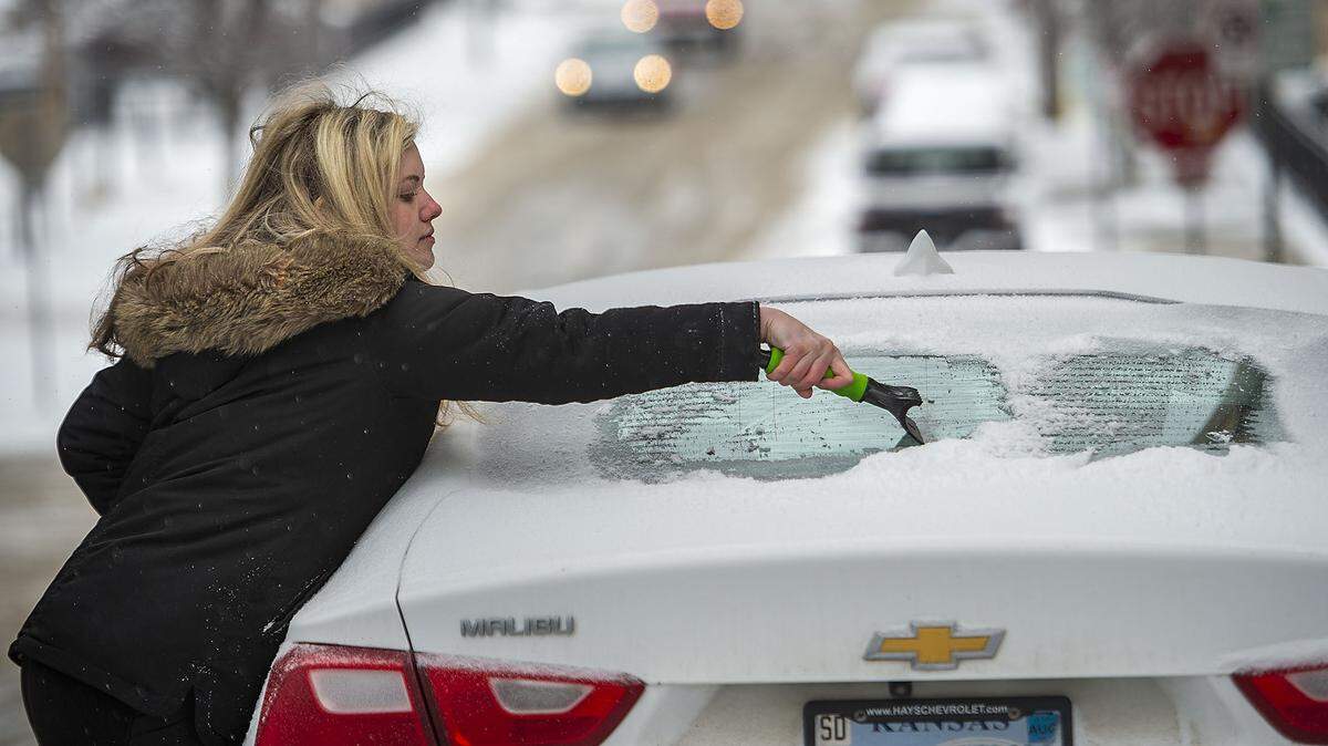 Braving the bitter cold, Carolyn Mense, who said she forgot her gloves, scraped snow and ice from the windows of her car Monday before leaving downtown Kansas City for a trip to Grinnell, Kansas.