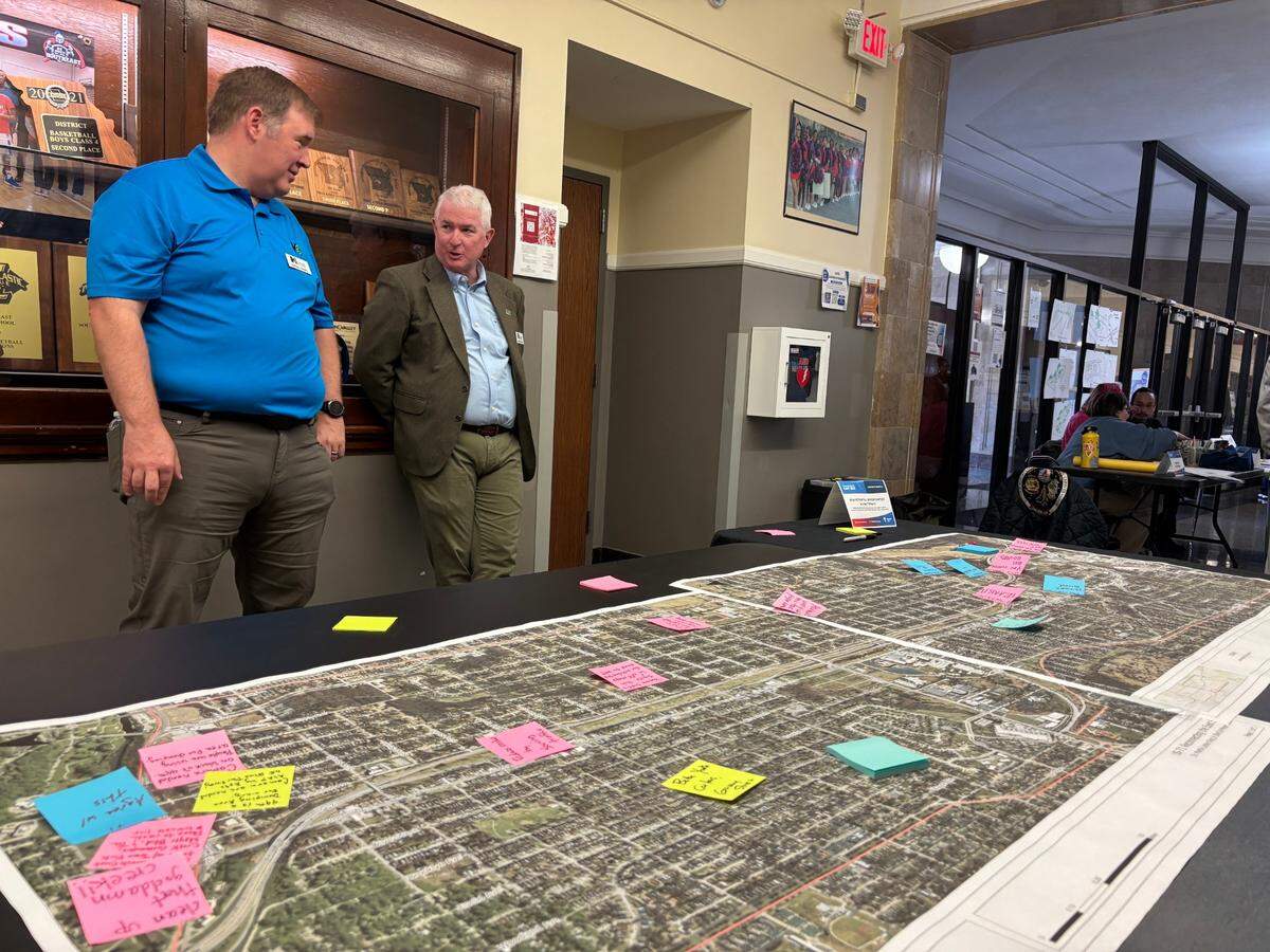 Two people with Hg Consult Inc. look over a map of 71 Highway at the Reconnecting the East Side meeting at Southeast High School on March 22.