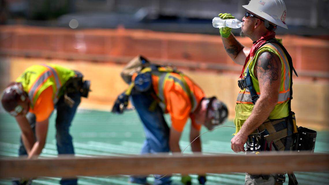 Daniel Dennis, an iron worker with Local 10, pauses for a cold drink of water while he and a crew from Three Feathers Construction tie rebar together at Truman Road and Baltimore Ave. on August 23, 2021.