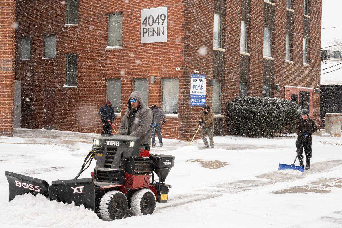 Snow removal crews blew snow off sidewalks in Westport on Saturday, January 24, 2026, in Kansas City. Subzero temps and light snow moved into the area overnight.