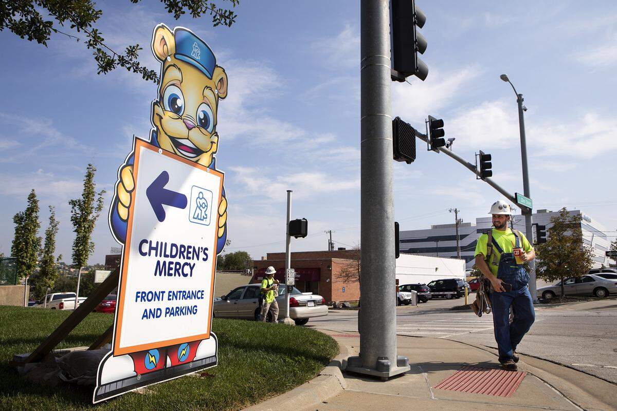 Dustin Gladbach, who works on the construction of a new building at Children’s Mercy Hospital, walks past a sign created by in-house artist Donald “Scribe” Ross.
