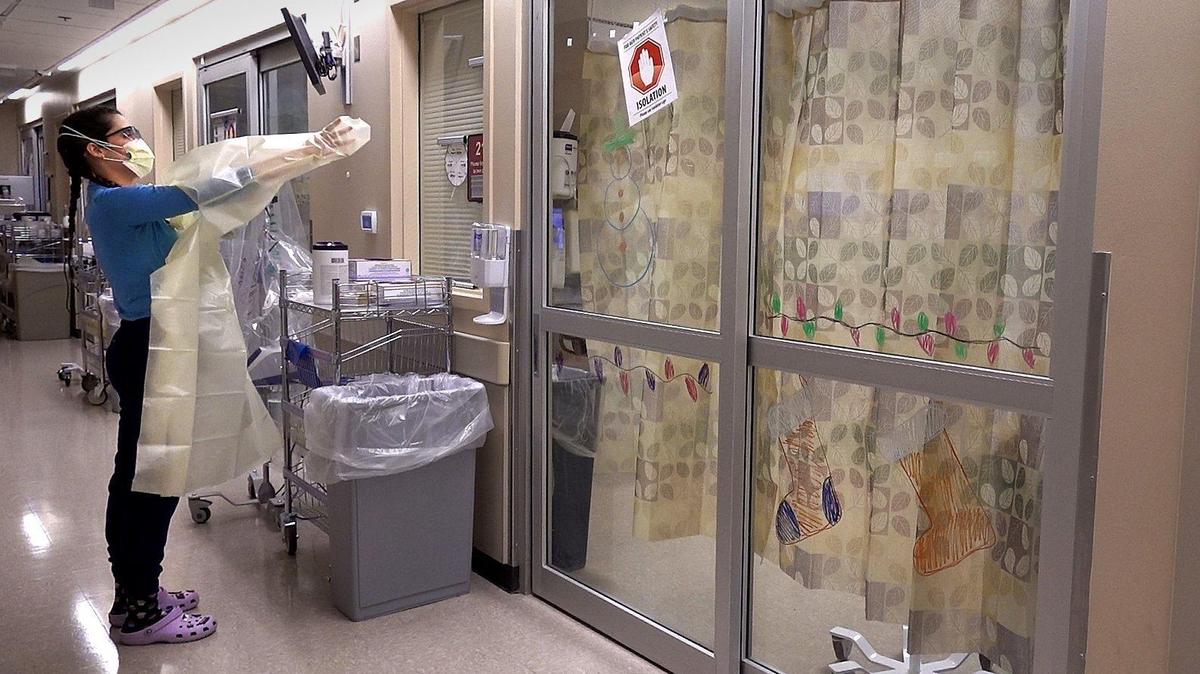 Delaney Swanson, a registered nurse in the COVID intensive care unit at University Health in Kansas City, enters a patient’s room for a visit. Like other hospitals, most of the patients there are unvaccinated.