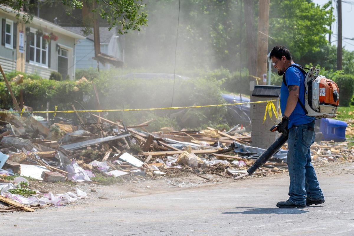 Carlos Garcia, a resident, clears debris with a leaf blower on Sunday, June 1, 2025, in Gladstone. He was helping clean up after a home explosion the day before that killed one person and scattered debris across the neighborhood.