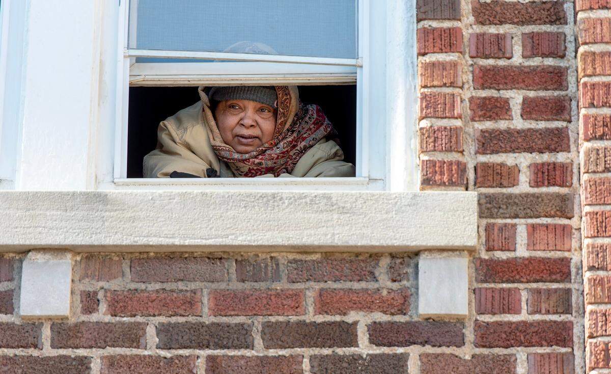 A woman, bundled up in winter clothing, looks out from her apartment on Jan. 23, 2023, in Kansas City. The multi-family housing unit had been without heat for days.