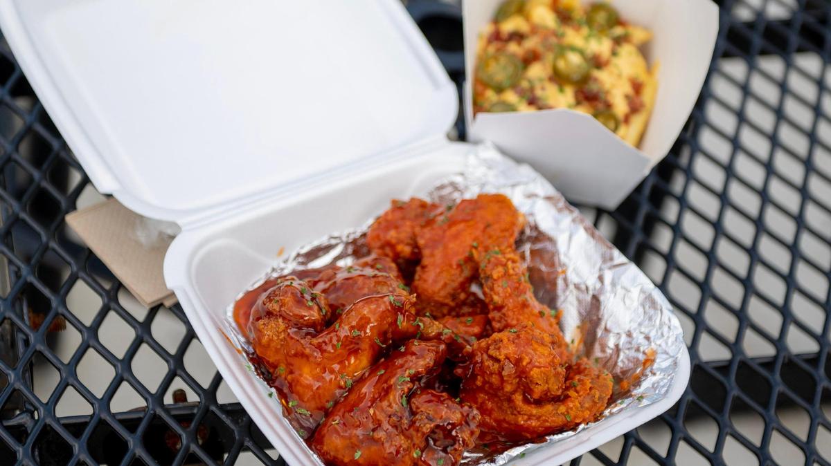 An order of jumbo wings — three dipped in honey hot sauce and three dipped in Buffalo sauce — with a side of loaded fries at What’s on your Plate? in Shawnee.