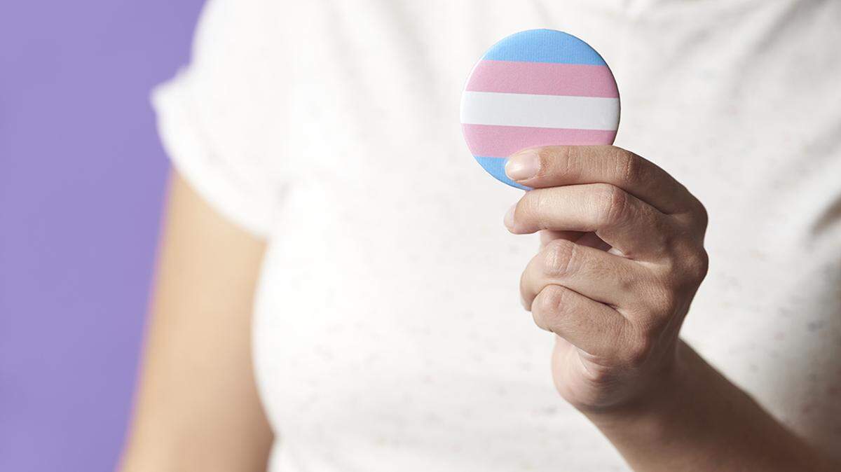 Person holding a trans flag badge or pin. Concepts of identity pride, gender diversity, equality and non discrimination. transgender