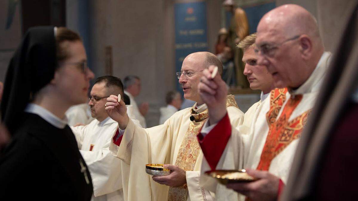 New Archbishop Shawn McKnight offering communion alongside the man he is succeeding, Archbishop Joseph F. Naumann, at McKnight’s Tuesday installation.