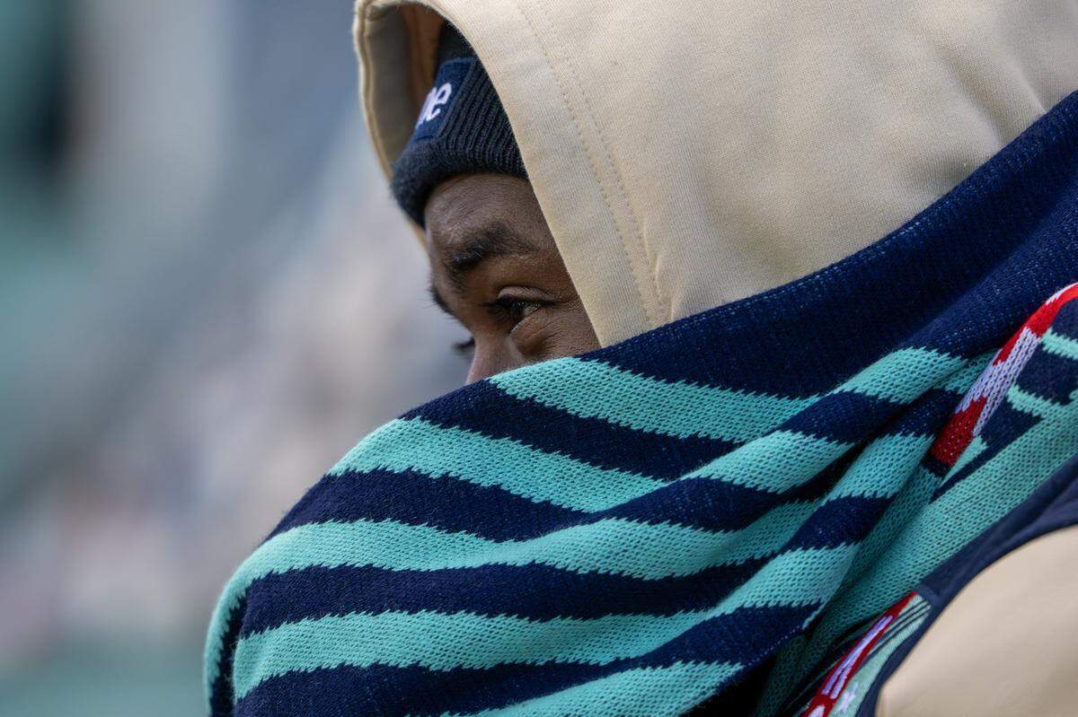 A fan sits wrapped in a scarf during the KC Current-Gotham NWSL quarterfinal playoff match at CPKC Stadium in Kansas City on Sunday, Nov. 9, 2025.