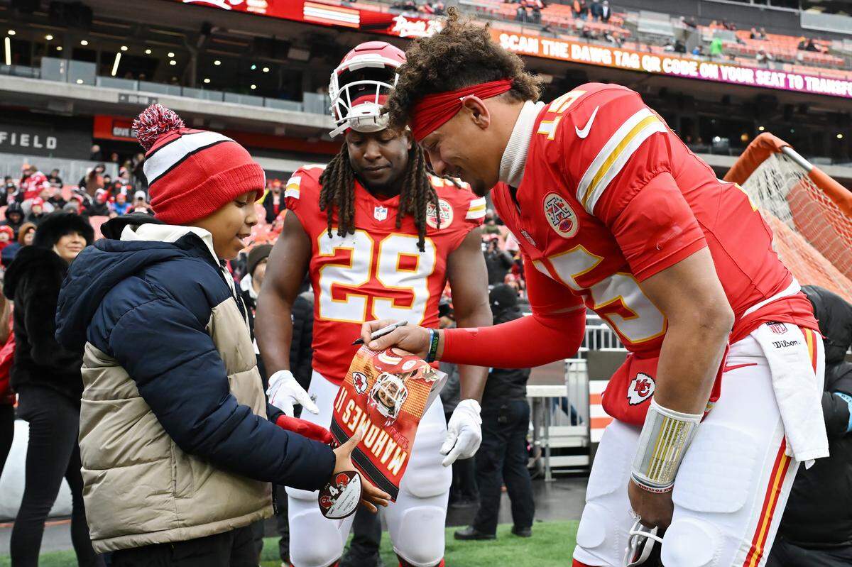 Patrick Mahomes #15 of the Kansas City Chiefs signs his autograph for a young fan before playing the Cleveland Browns at Huntington Bank Field on December 15, 2024 in Cleveland, Ohio.
