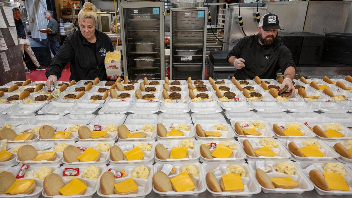Christina Ferchichi, left, and Travis Shklar, put together 120 cheeseburgers with potato salad at the Westport Flea Market, where school lunches now account for 70 percent of the business’s revenue.