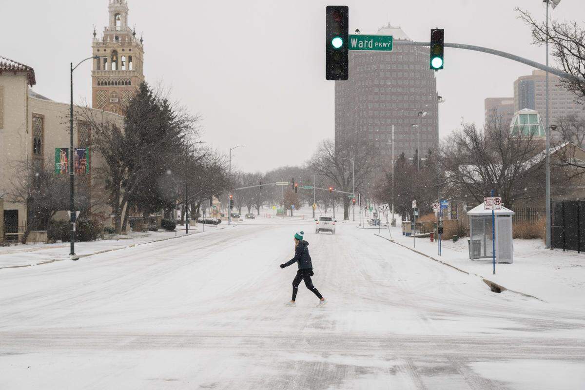 A woman walks in the street along Ward Parkway near the Country Club Plaza on Saturday, January 24, 2026. Subzero temps and light snow moved into the area overnight.