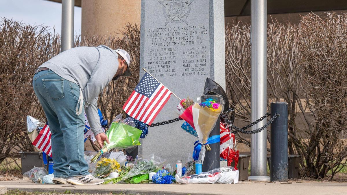 Paul Nou of Grain Valley places flowers at the Independence Police Department memorial for fallen officers Friday for police officer Cody Allen. Allen, along with Jackson County civil process server Drexel Mack, were both shot and killed Thursday after Mack attempted to serve an eviction notice.