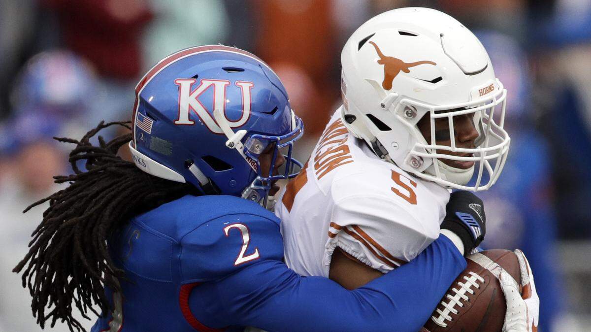 Kansas cornerback Corione Harris hauled down Texas running back Tre Watson during the first half of Saturday’s game in Lawrence.