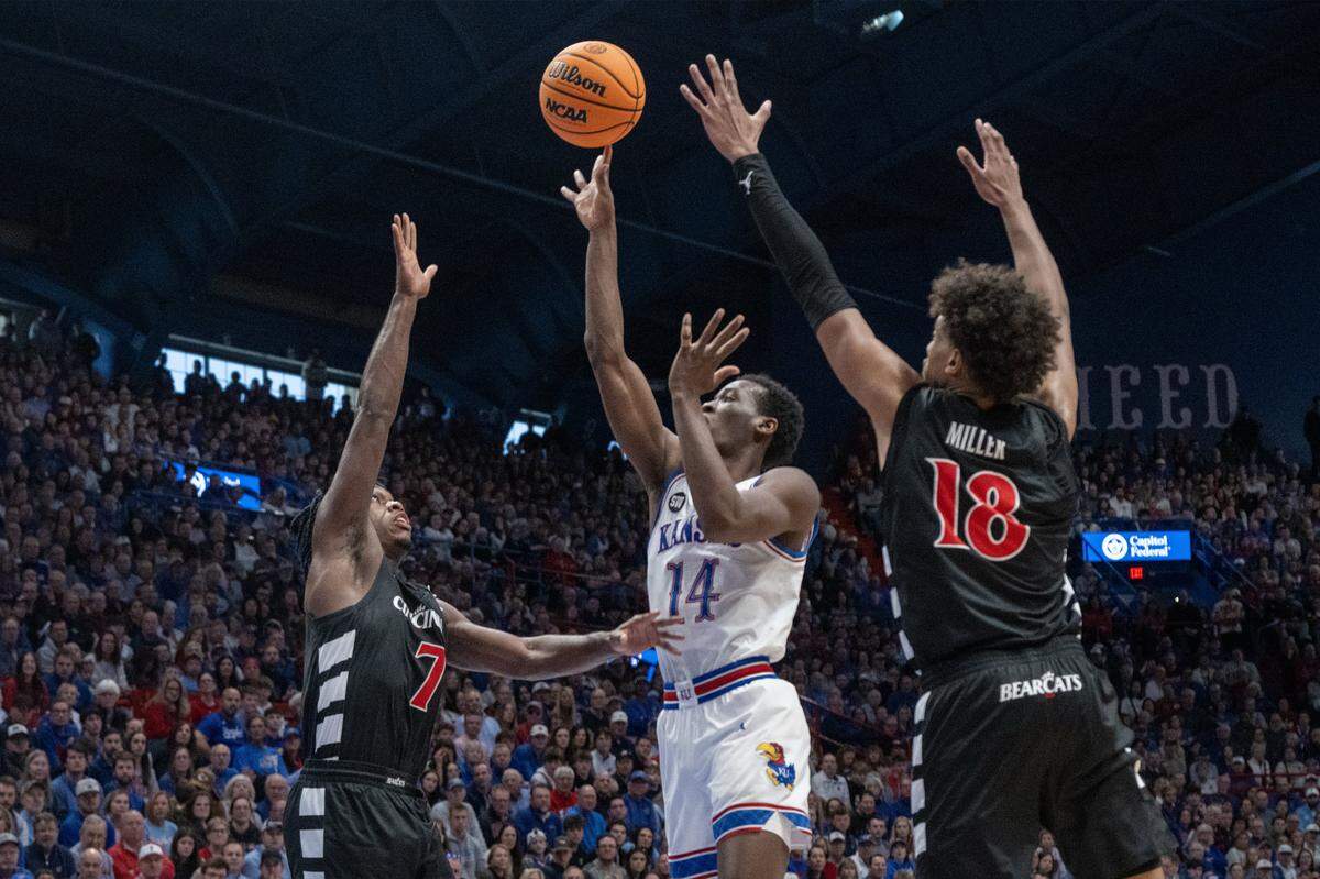 Kansas Jayhawks guard Melvin Council Jr. (14) shoots as Cincinnati Bearcats guard Keyshuan Tillery (7) and Cincinnati Bearcats forward Baba Miller (18) defend in the second half Allen Fieldhouse on Saturday, Feb. 21, 2026, in Lawrence, Kansas.