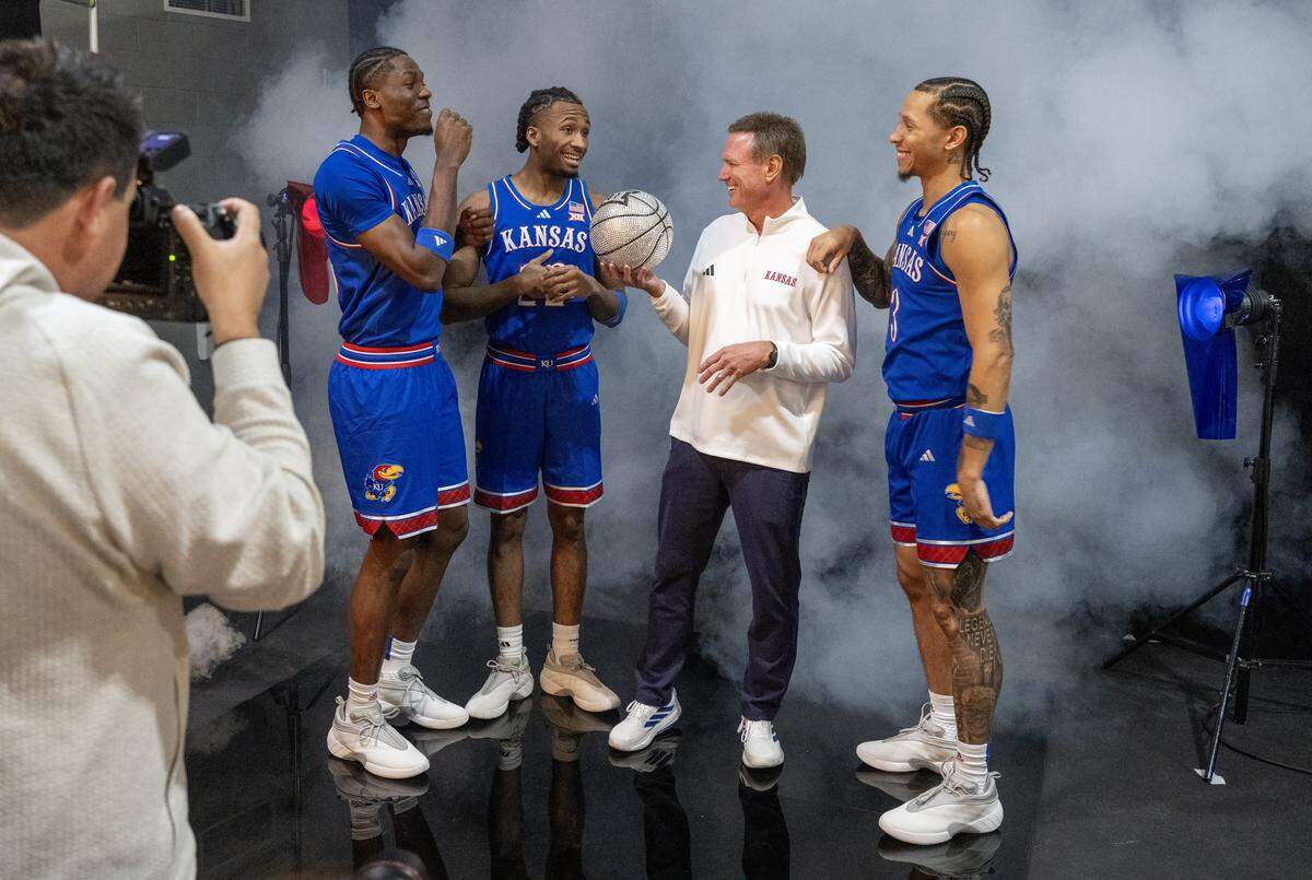 Kansas basketball players Flory Bidunga (40), Darryn Peterson (22) and Tre White (3) have their photo taken with coach Bill Self during Big 12 Basketball Media Day at T-Mobile Center on Wednesday, October 22, 2025, in Kansas City.
