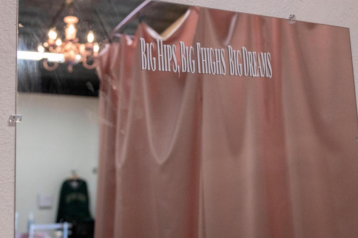 A mirror where customers try on clothes includes a sticker promoting body positivity.