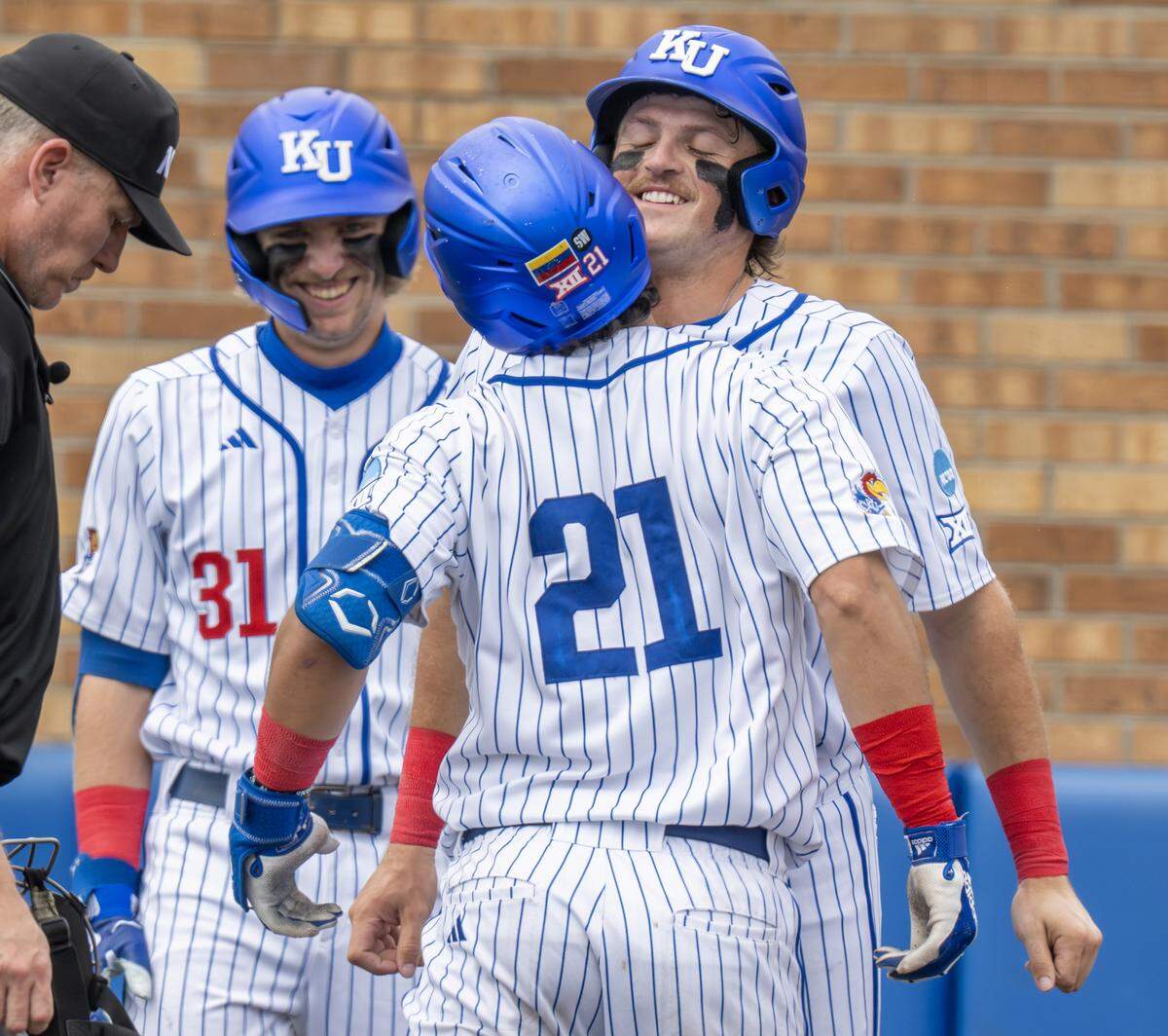 Kansas Jayhawks catcher Augusto Mungarrieta (No. 21) celebrates with teammates Jordan Bach (31) and Josh Dykhoff (16) after hitting a home run against the Northeastern Huskies in the second inning of an NCAA baseball tournament game at Hoglund Ballpark on Friday, May 29, 2026, in Lawrence.