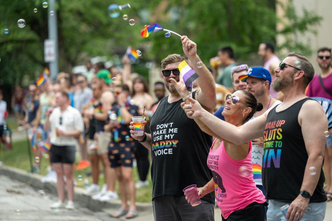 R.J. Battreall, from left, and his husband, Oliver Benbrook, right, of Kansas City, and Sheila Sheridan, grabbed for the bubbles as they watched the KC Pride Parade.