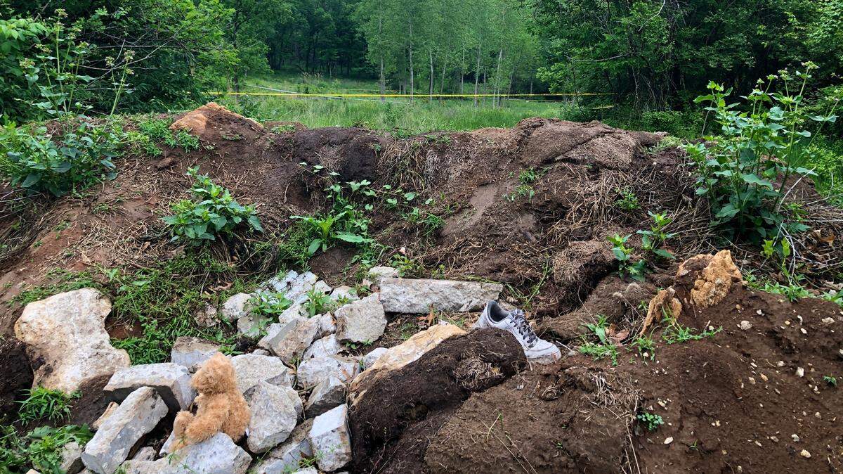 A teddy bear sits on a pile of rocks off Pittman Road, close to East 41st Street, near the entrance to a field where a small baby was found dead Saturday, May 13, 2023, Kansas City police said. Crime scene tape remained up two days later.
