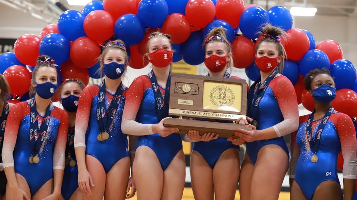Olathe North’s gymnasts show off their first-place trophy and individual hardware earned Saturday in the Kansas state championship meet at Shawnee Mission West.