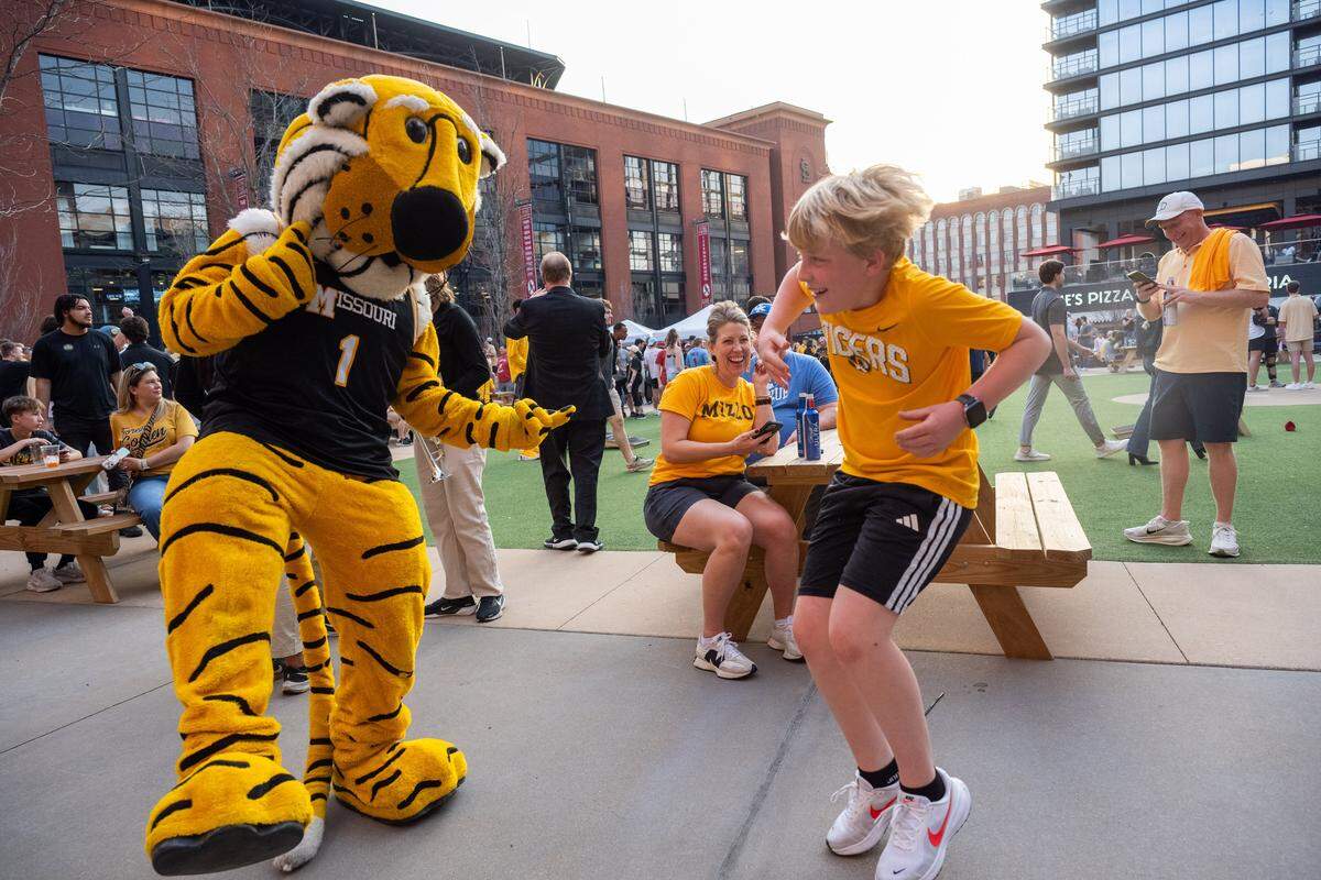 Henry Hohman, 11, dances with Truman the Tiger at the Mizzou Spirit Rally at Ballpark Village on Friday, March 20, 2026, in St. Louis. The Missouri Tigers faced off against the Miami Hurricanes in the first round of the NCAA Men's Basketball Tournament in St. Louis.