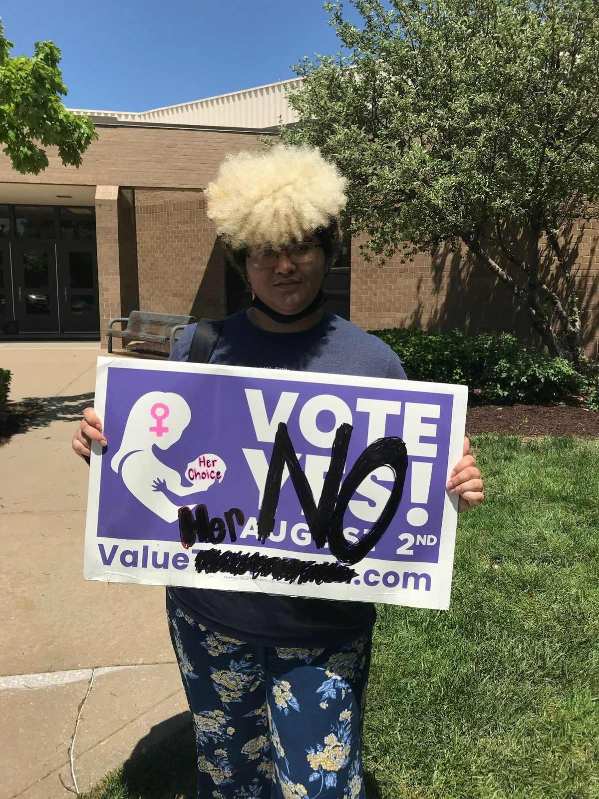 Blue Valley North High School student Zenyth Capitman poses with a sign opposing Kansas’ upcoming ballot initiative that would remove the right to abortion from the state’s constitution. Capitman helped organize a walkout protest at the school on Thursday, May 12.