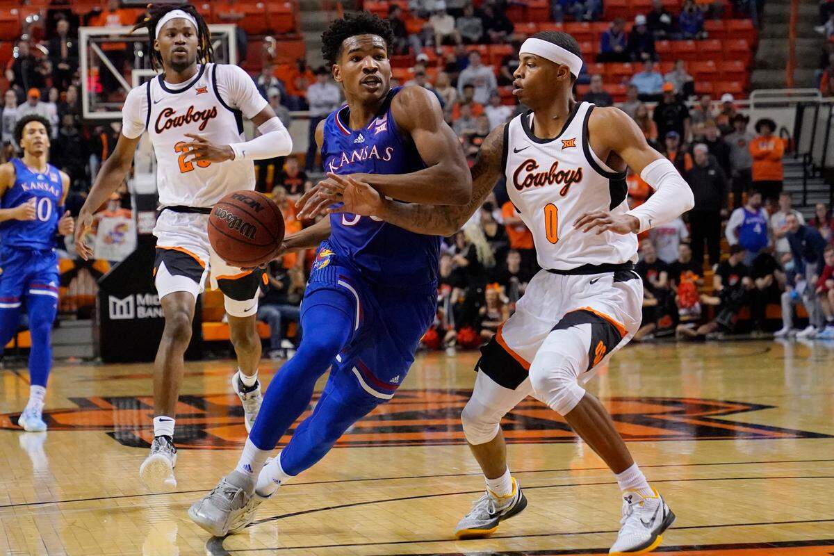 Kansas guard Ochai Agbaji, center, drives around Oklahoma State guard Bryce Thompson (1) in the first half of an NCAA college basketball game Tuesday, Jan. 4, 2022, in Stillwater, Okla. (AP Photo/Sue Ogrocki)