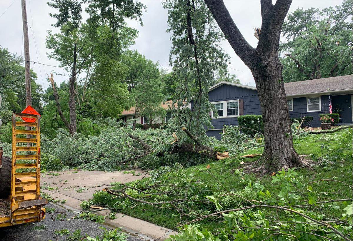 Tree limbs are strewn across a yard on Windsor Street near 95th Street in Leawood, Kansas, on Wednesday morning after overnight tornadoes. Lawn care services and neighbors worked through the morning to assess the damage across the neighborhood.
