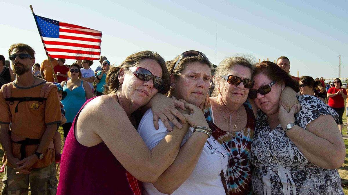 Three sisters and a daughter, Susan Sims (left), Jen Brown, Linda Sonaty and Lisa Johnson (right) held each other as the town gathered for a moment of silence at 5:41p.m. on Sunday, May 29, 2011, in Joplin, Missouri to mark the time when the EF 5 tornado struck their town last week. Some of their family members lost their homes, but no one in the family died in the storm. (Photo by SHANE KEYSER/Staff)