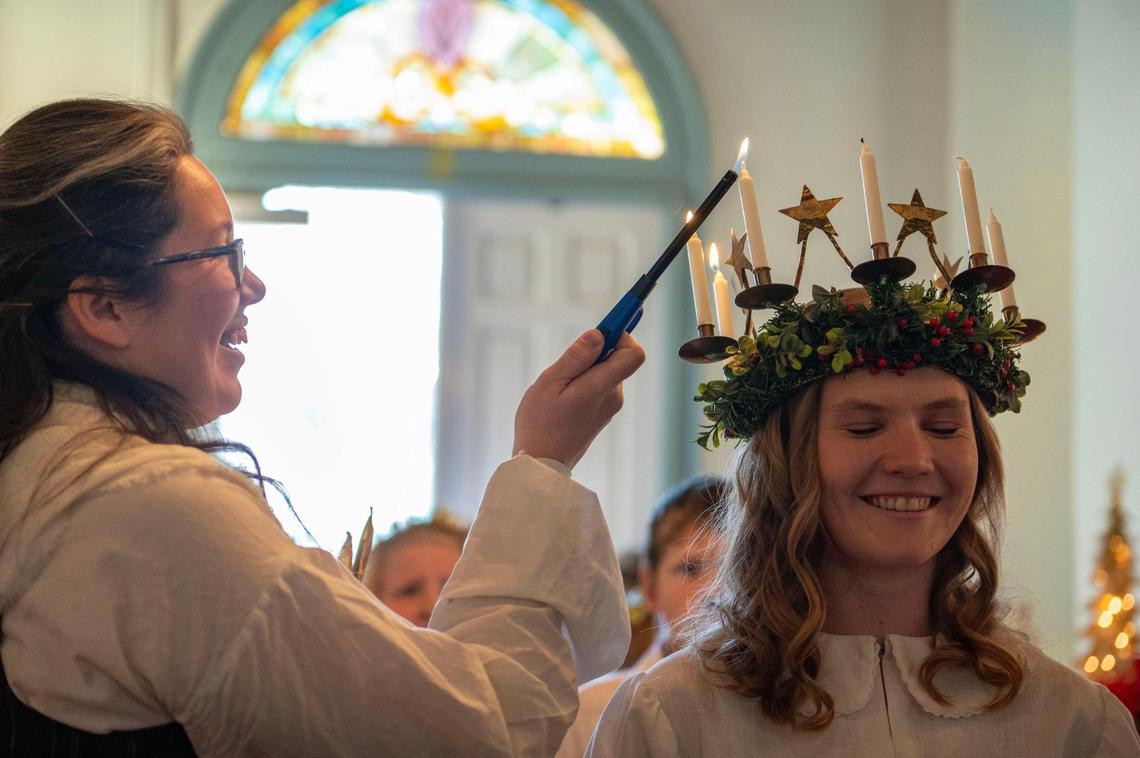 Natalie Nelson, left, lights the head candelabra for Capbell Gaskill during the St. Lucia Festival in Lindsborg.